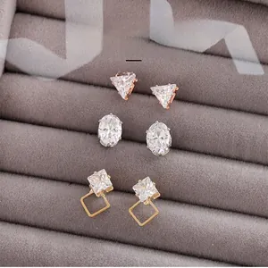 Detailed view of three pairs of geometric cubic zirconia stud earrings in a velvet tray