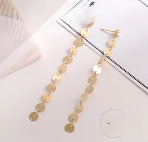 Detail of long gold tassel drop earrings featuring linked metallic discs and zircon stud
