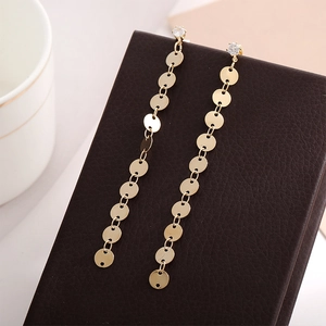 Elegant gold-plated tassel earrings with small diamond studs on a leather texture