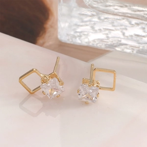 Minimalist square geometric gold stud earrings with sparkling cubic zirconia on marble background