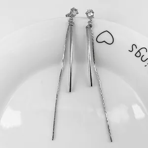 Minimalist silver long tassel earrings with sparkling zircon stud on a white ceramic plate