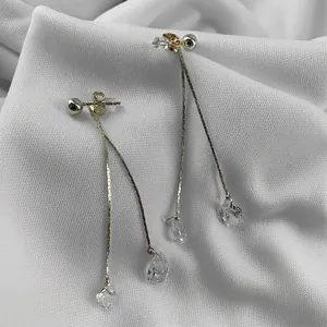 Elegant gold drop earrings with sparkling water drop crystals on white textured fabric