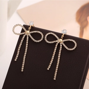 Boucles d'oreilles papillon dorées avec pampilles et cristaux sur un écrin en cuir