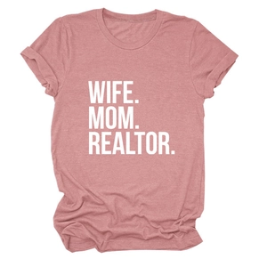 Close-up of WIFE MOM REALTOR bold white lettering on a dusty rose cotton t-shirt