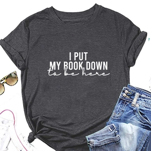 Flat lay of charcoal gray t-shirt with I Put My Book Down slogan and casual accessories