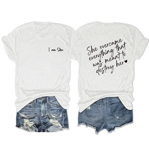 Detailed view of the inspirational 'She overcame everything' text on white cotton T-shirt