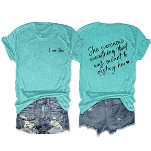 Detail of blue T-shirt with 'She overcame everything' quote and ripped denim shorts