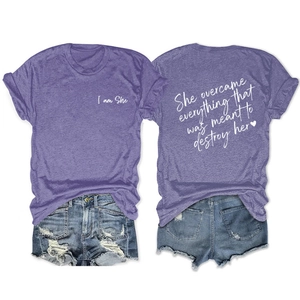 Flat lay of purple 'I am She' short sleeve tee and ripped denim shorts on white background