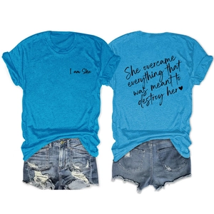Flat lay of women's bright blue t-shirt with 'I am She' text and ripped denim shorts