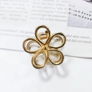 Detailansicht einer goldfarbenen, hohlen Blumen-Haarklammer auf minimalistischem Grund