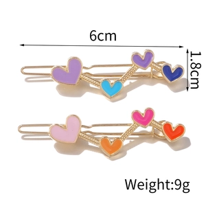 Set of two colorful heart-shaped alloy hair clips with gold finish on white background