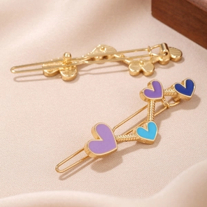 Golden heart-shaped hair clips set with colorful enamel finish on elegant silk background
