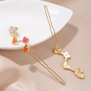 Pair of golden metal hair clips with four colorful hearts on silk champagne fabric
