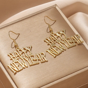 Detail showing shiny gold Happy New Year letter earrings on champagne velvet