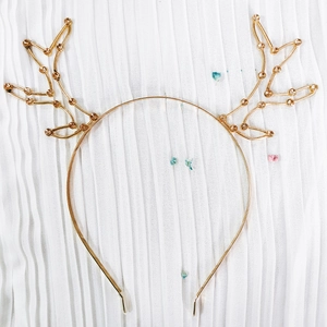 Golden reindeer antler headband with amber rhinestones on a white fabric background
