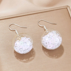 Vue macro de boucles d'oreilles de Noël avec sphères transparentes et paillettes étoilées