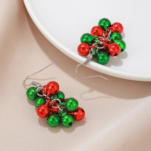 Détail de boucles d'oreilles de Noël avec cloches rouges et vertes sur céramique blanche