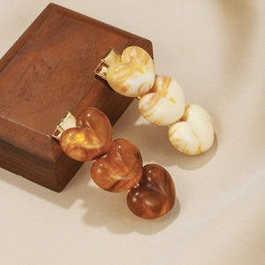 Retro acrylic heart hair clips in beige and amber tones on silk background