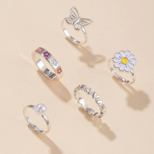 Set di 5 anelli d'argento con margherite, farfalle, perle e cuori su sfondo rosa tenue
