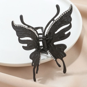 Détail d'une pince à cheveux papillon noir mat ornée de strass brillants et élégants