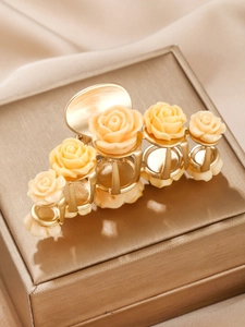 Detail of cream resin rose hair claw clip with gold metal base on champagne silk