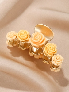 Macro detail of champagne resin roses on a polished gold metal hair claw clip