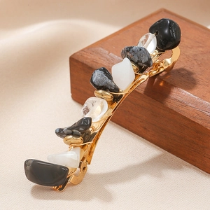 Artistic gold spring hair clip with mixed natural stones on a warm textured background