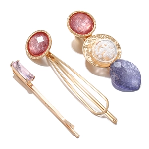 Dreiteiliges goldenes Haarklammer-Set mit rosa Edelsteinen und Perlen auf weißem Grund