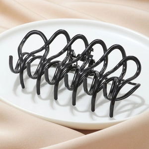 Grande pince à cheveux papillon noir brillant posée sur une assiette en céramique