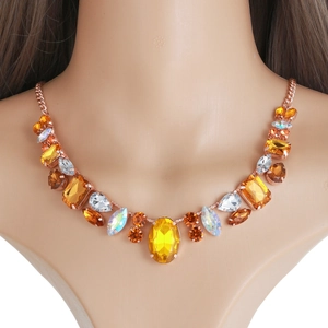 Gros plan du collier en or rose avec de gros cristaux facettés couleur ambre et aurore