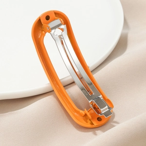 Macro detail of bright orange spring hair clip with durable silver metal mechanism