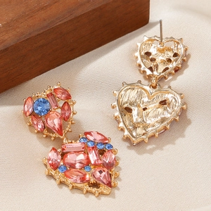 Macro shot of double heart dangle earrings with pink and blue crystals in gold setting