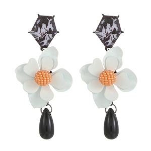 Detailed view of floral drop earrings with ink-patterned geometry and black pendants