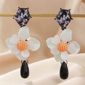 Detail of floral drop earrings with white flower petals and black teardrop pendant