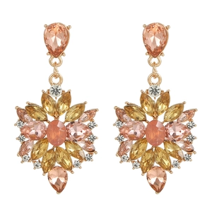 Macro detail of golden flower earrings with amber, champagne, and pink crystals