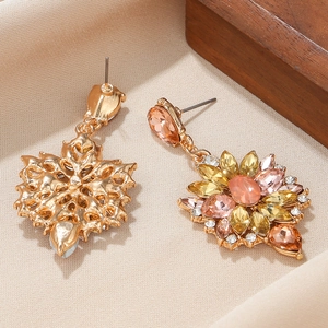 Detail of floral drop earrings with pink and amber gemstones on silk fabric