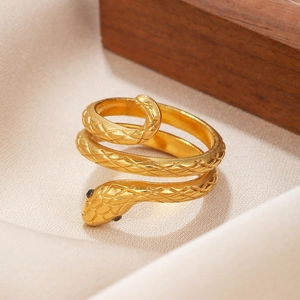 Detail of gold snake ring with scale texture and black gemstone eyes on silk
