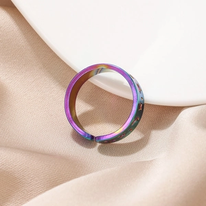 Macro shot of iridescent rainbow star and moon engraved adjustable ring on white ceramic tray