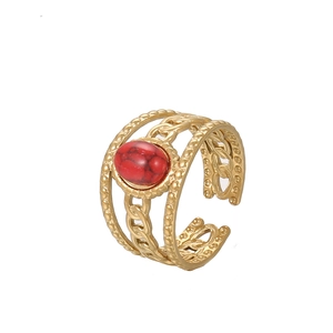 Macro detail of gold-plated snake ring featuring three-layer chain texture and red stone