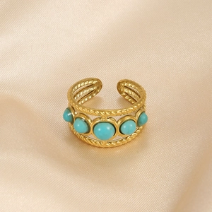 Detailed close-up of gold plated snake ring with five turquoise gems and twisted texture