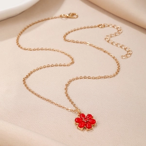 Macro detail of golden flower necklace with red enamel petals and central crystal