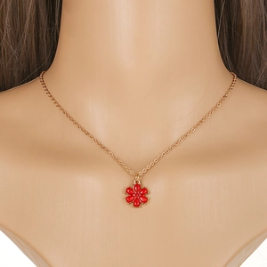 Detailed view of a gold necklace with a red six-petal flower pendant on a model