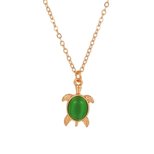 Detail of rose gold sea turtle necklace featuring a green cat-eye stone and carved texture