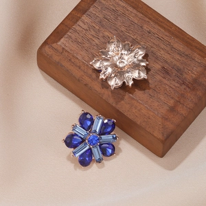 Elegant rose gold sunflower stud earrings with blue gemstones and crystals on silk