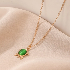 Elegant gold chain necklace with a green cat-eye stone turtle pendant on silk