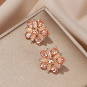Close-up of rose gold floral stud earrings with champagne crystals on satin fabric