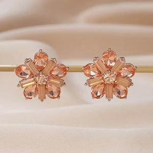 Elegant champagne gold flower earrings with crystals hanging on a metallic stand