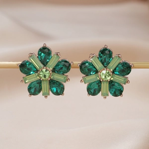 Elegant green crystal flower stud earrings with rose gold base on silk background