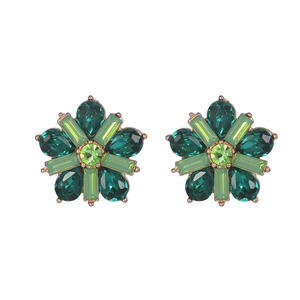 Close-up of gold flower earrings with emerald green crystals on white background