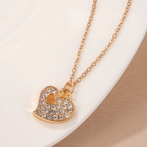 Detailed close-up of a golden heart pendant necklace with sparkling rhinestones on ceramic